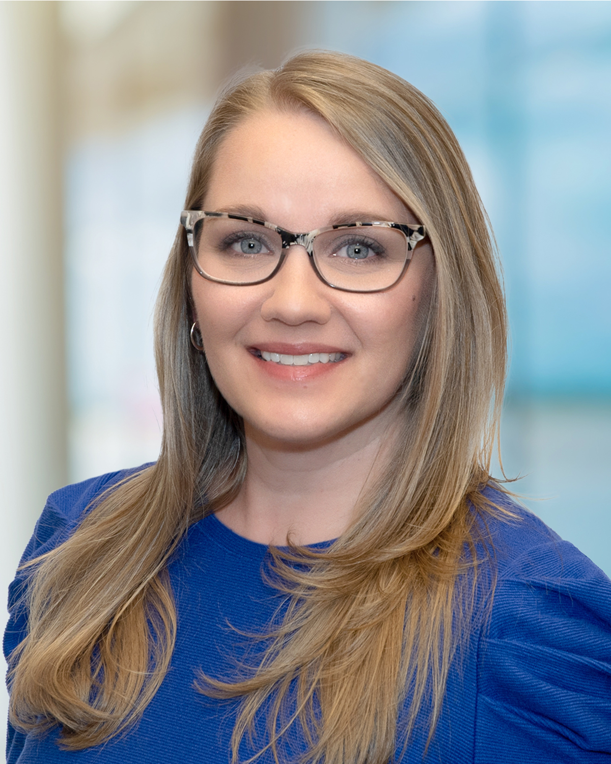 woman with blonde hair, glasses, and blue shirt